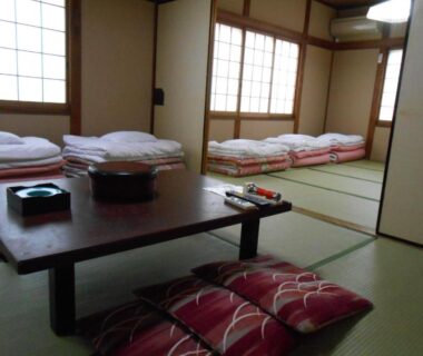 Tatami room with futon bedding, low table and shoji screens at Ryokan Matsushima in Kanagawa, Japan