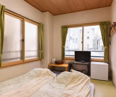Tatami room with futon bedding, low table, TV and city view at Ryokan Mikawaya, Tokyo