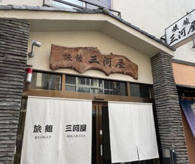 Entrance with white noren and wooden signboard at Ryokan Mikawaya in Tokyo, Kantō, Japan