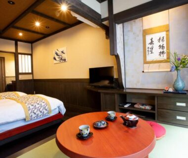 Tatami floor room with twin beds, low red lacquer table, tokonoma alcove and shoji screens at Ryokan Misato in Kumamoto