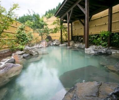 Rock-edged outdoor onsen with wooden shelter and bamboo fence at Ryokan Misato, Kumamoto, Kyushu, Japan