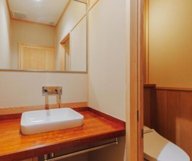 Compact wooden sink area with mirror and modern toilet at Ryokan Motonago in Kyoto, Kansai, Japan