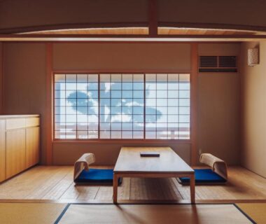 Tatami-floored guest room with low wooden table, floor cushions and shoji screen window at Ryokan Motonago in Kyoto