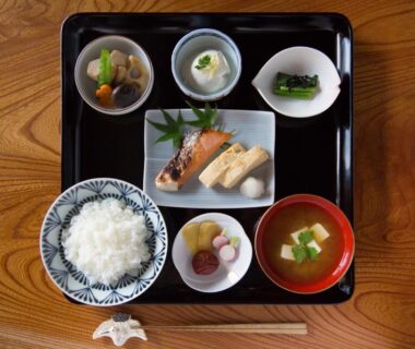 Rice, grilled fish, miso soup and side dishes on wooden tray at Ryokan Mugen Kyoto