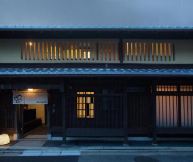 Evening exterior with wooden lattice and lit entrance at Ryokan Mugen Kyoto