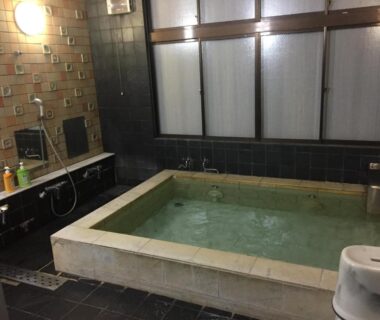 Tiled indoor onsen bath with stools and shower area at Ryokan Murayama in Gifu, Chūbu, Japan