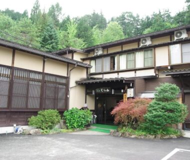 Exterior entrance of Ryokan Murayama with wooden facade and shrubs in Gifu, Chūbu, Japan