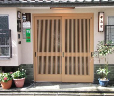 Wooden latticed entrance doors with potted plants at Ryokan Nakajimaya in Kyoto Kansai
