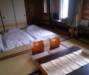 Traditional tatami room with futon bedding, low table and floor chairs at Ryokan Nakajimaya in Kyoto