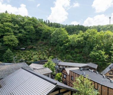 Tiled roofs of Ryokan Nanjoen nestled among lush green hills in Kumamoto, Kyushu