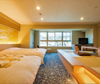 Spacious tatami room with futon beds, raised seating area and large window at Ryokan Nenrinbo in Kyoto
