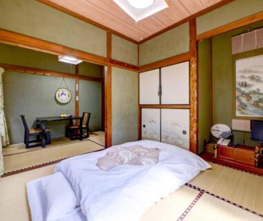 Traditional tatami room with futon, low table, sliding fusuma doors and tokonoma with hanging scroll at Ryokan Niko Tokyo
