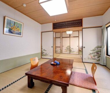 Tatami room with low wooden table, cushions and painted fusuma at Ryokan Niko in Tokyo