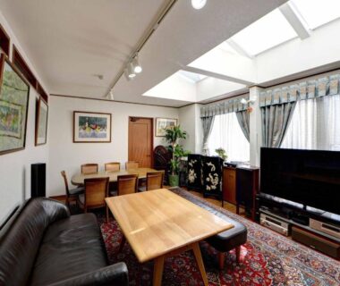 Skylight lounge with sofa, wooden table, chairs and television on patterned rug at Ryokan Niko Tokyo