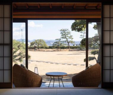 Tatami room with low table and wicker chairs opening to garden, Ryokan Onomichi Nishiyama, Hiroshima