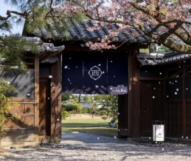 Traditional wooden gate with noren and garden path at Ryokan Onomichi Nishiyama, Hiroshima
