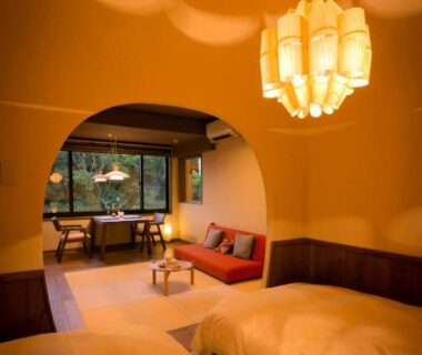 Warm tatami room with two low beds, arched partition and garden view at Ryokan Oomuraya, Saga, Kyūshū, Japan