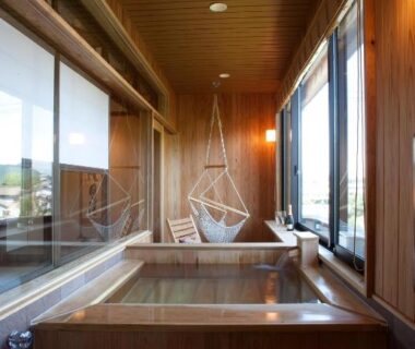 Wooden soaking tub with hanging chair and large windows at Ryokan Oomuraya in Saga, Kyūshū, Japan