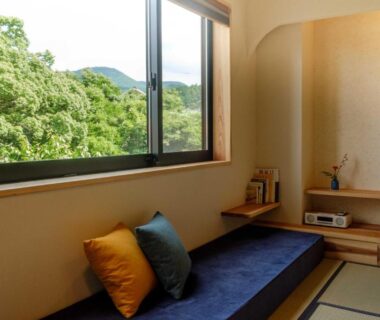 Tatami room with low bench and cushions overlooking green hills at Ryokan Oomuraya in Saga, Kyūshū, Japan