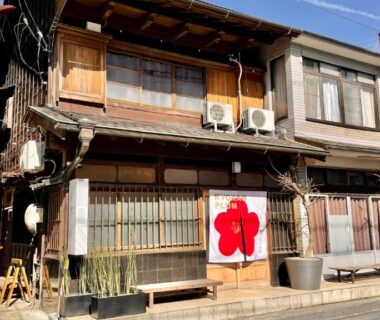 Two-story wooden facade with red noren at Ryokan Plum in Kanagawa