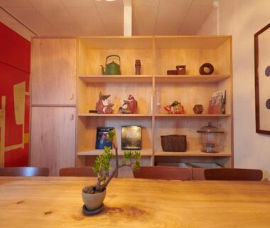 Small potted plant on wooden table with display shelves and ceramics at Ryokan Plum in Kanagawa, Kantō