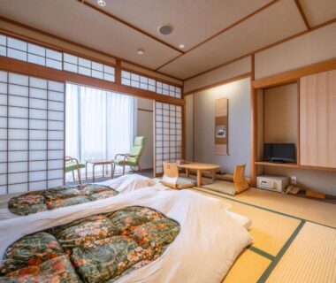 Tatami room with futons, shoji screens, low table and seating at Ryokufuso in Kyoto