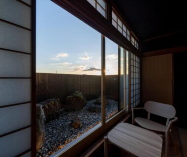 Tatami room with shoji screens and chair overlooking a small rock garden and sky in Ryokan Ryokufuso Kyoto