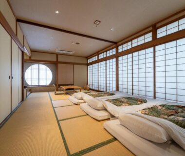 Traditional tatami room with futons, shoji screens and round window at Ryokan Ryokufuso in Kyoto, Kansai, Japan