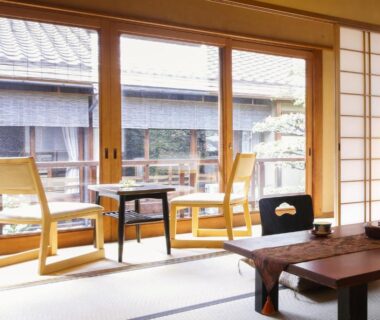 Tatami room with low table and chairs by shoji windows at Ryokan Sanga Kyoto