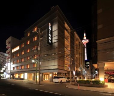 Illuminated ryokan exterior with Kyoto Tower in background at Ryokan Sanoya, Kyoto, Kansai, Japan