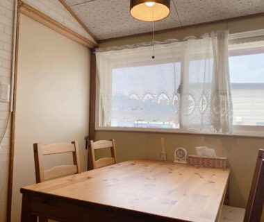 Sunlit wooden dining table and chairs in a simple room at Ryokan Sansui, Hokkaidō