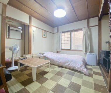 Traditional tatami room with futon, low table, shoji window, fan and TV at Ryokan Sansui in Hokkaidō