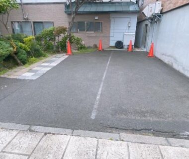 Small paved parking space with traffic cones beside Ryokan Sansui entrance in Hokkaidō