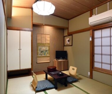 Tatami room with low table, cushions and shoji screens at Ryokan Sansuiso in Tokyo