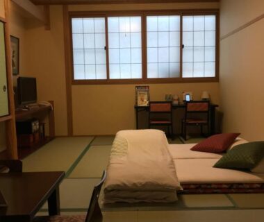 Tatami room with futon bedding, shoji windows, low table and cushions at Ryokan Sawaya Honten, Kyoto