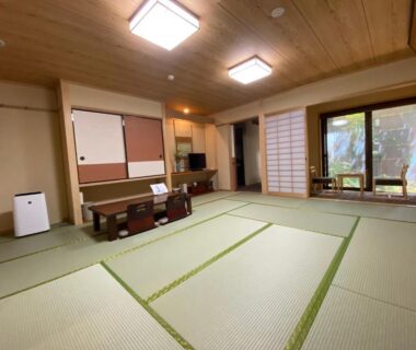 Spacious tatami room with low table, shoji screens and garden view at Ryokan Sawaya Honten in Kyoto