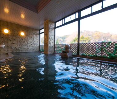 Large indoor bathing area with tiled walls and panoramic windows at Ryokan Seishounagon, Mie, Kansai