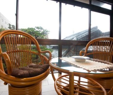 Two rattan chairs and glass table by window at Ryokan Sennari, Ōita, Kyushu
