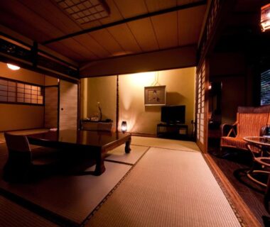 Traditional tatami room with low table, shoji screens and wooden seating, warm ambient lighting at Ryokan Sennari in Ōita