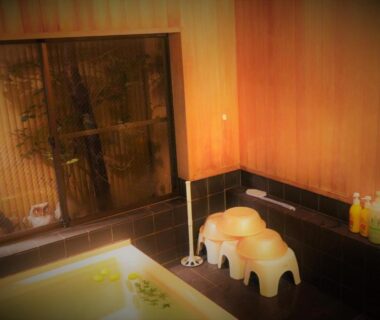 Indoor onsen bath with washing stools, toiletries and wooden walls at Ryokan Shimizu, Kyoto