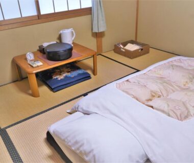 Tatami room with futon, low table, kettle and shoji window at Ryokan Shimizu Kyoto