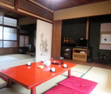 Traditional tatami room with low red lacquer table, zabuton cushions, shoji screens and tokonoma in Ryokan Taishoro, Nara