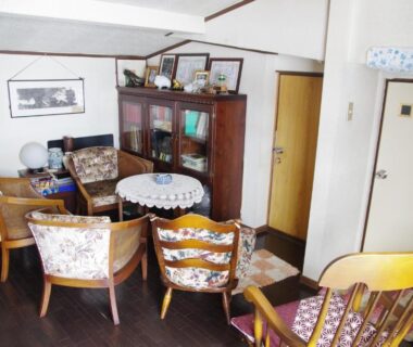 Cozy sitting area with wooden chairs, round table and bookshelf at Ryokan Takayama in Gifu
