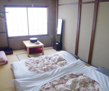Traditional tatami room with two futons, low chabudai table, shoji window and wooden accents at Ryokan Takayama, Gifu