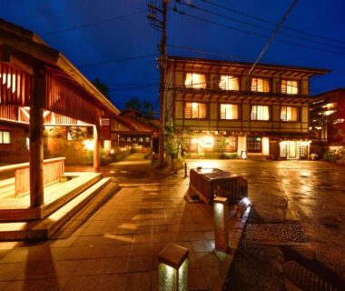 Traditional wooden ryokan exterior at night Ryokan Tamura in Gunma Kantō with lit entrance and wet stone path