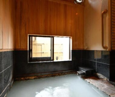 Milky onsen bath with wooden walls and small window at Ryokan Tamura in Gunma