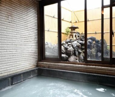 Milky indoor onsen bath with sliding glass doors and rock garden, Ryokan Tamura, Gunma, Kanto