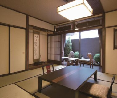 Traditional tatami room with low table, zabuton cushions and sliding shoji opening to a small courtyard at Ryokan Tanabe