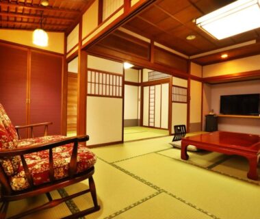 Spacious tatami room with low table, shoji screens and wooden beams at Ryokan Tanabe, Gifu