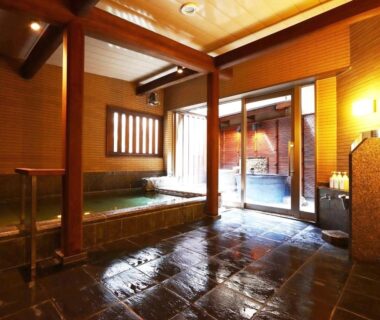 Indoor onsen bath with wooden pillars and stone floor at Ryokan Tanabe in Gifu, Chūbu